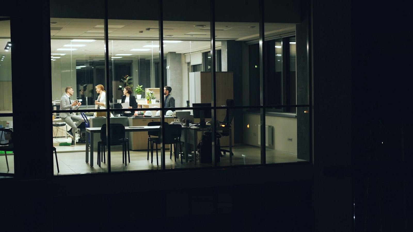 Oficina iluminada de noche con personas trabajando